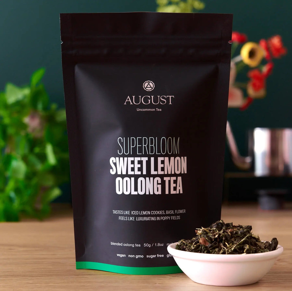 Black bag of Sweet Lemon Oolong Tea for energy and fitness health, beside a small white bowl of loose leaf tea blend on a wooden table.