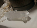 Natural clear quartz crystal point resting on white cloth near silver cup and macrame as new arrival decor.