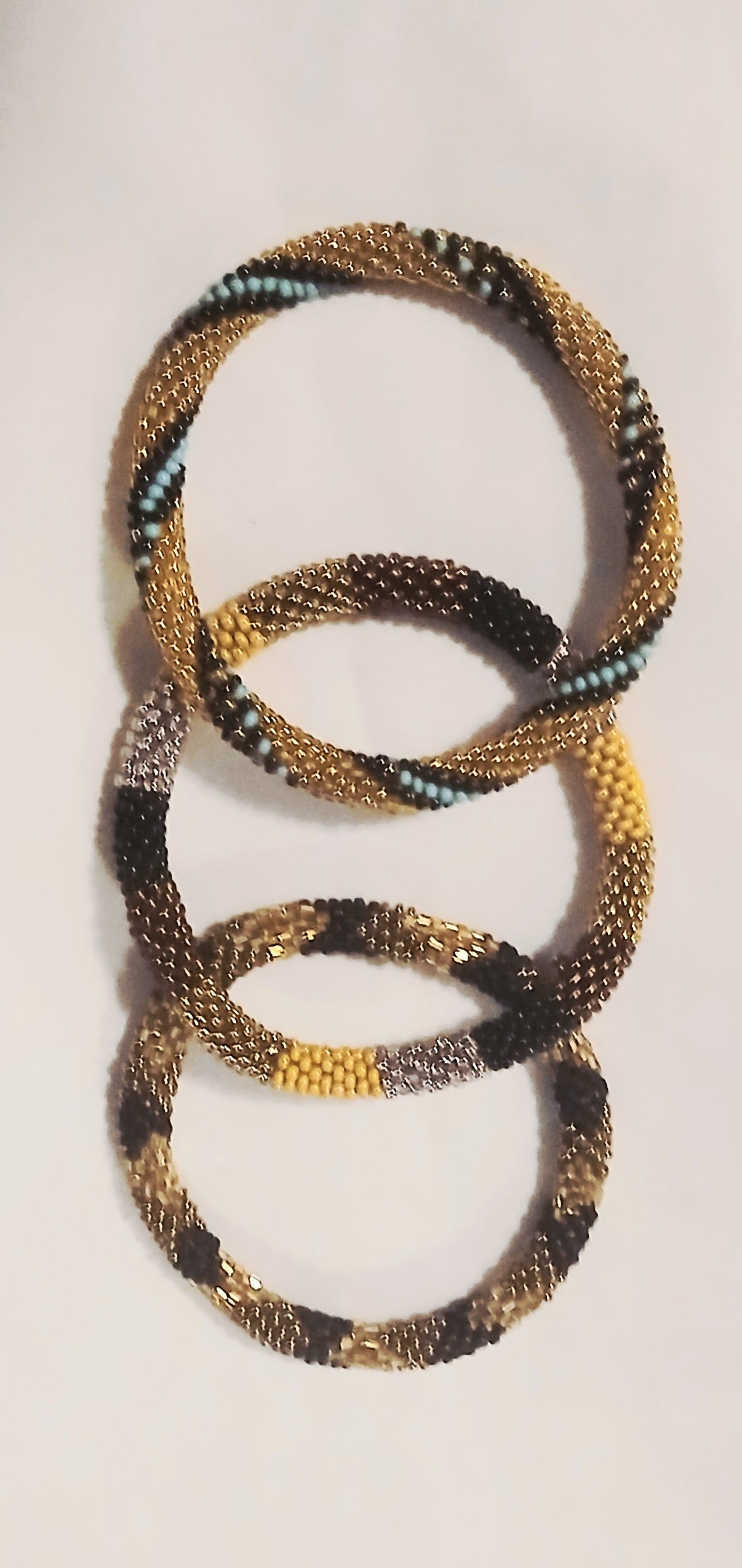 Handwoven Nepal bracelets featuring intricate gold, black, and turquoise beadwork in a stacked loop design.