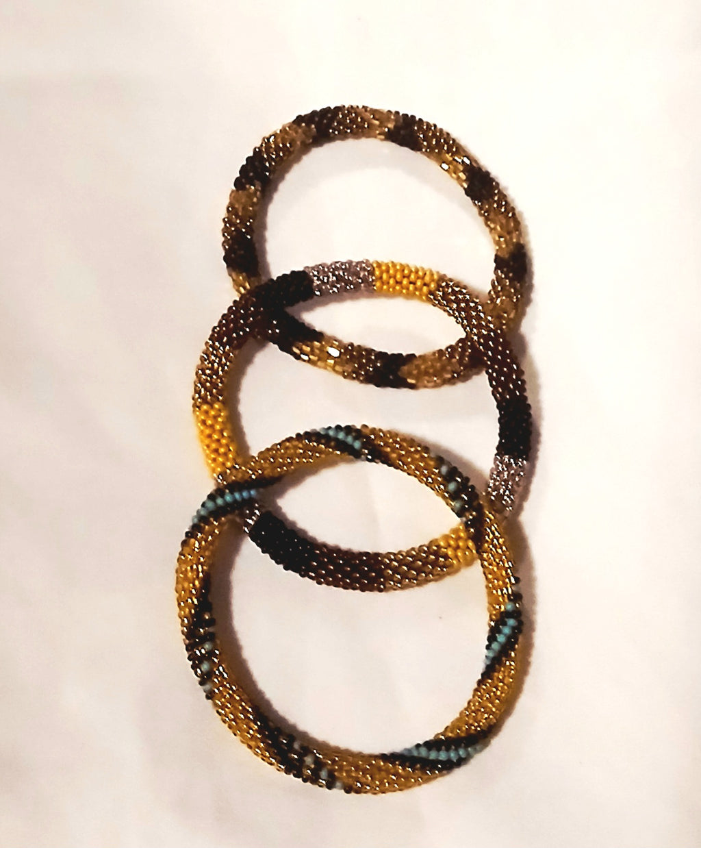 Handmade Nepal bracelets featuring intricate gold, black, and teal beadwork in a stacked circular design.